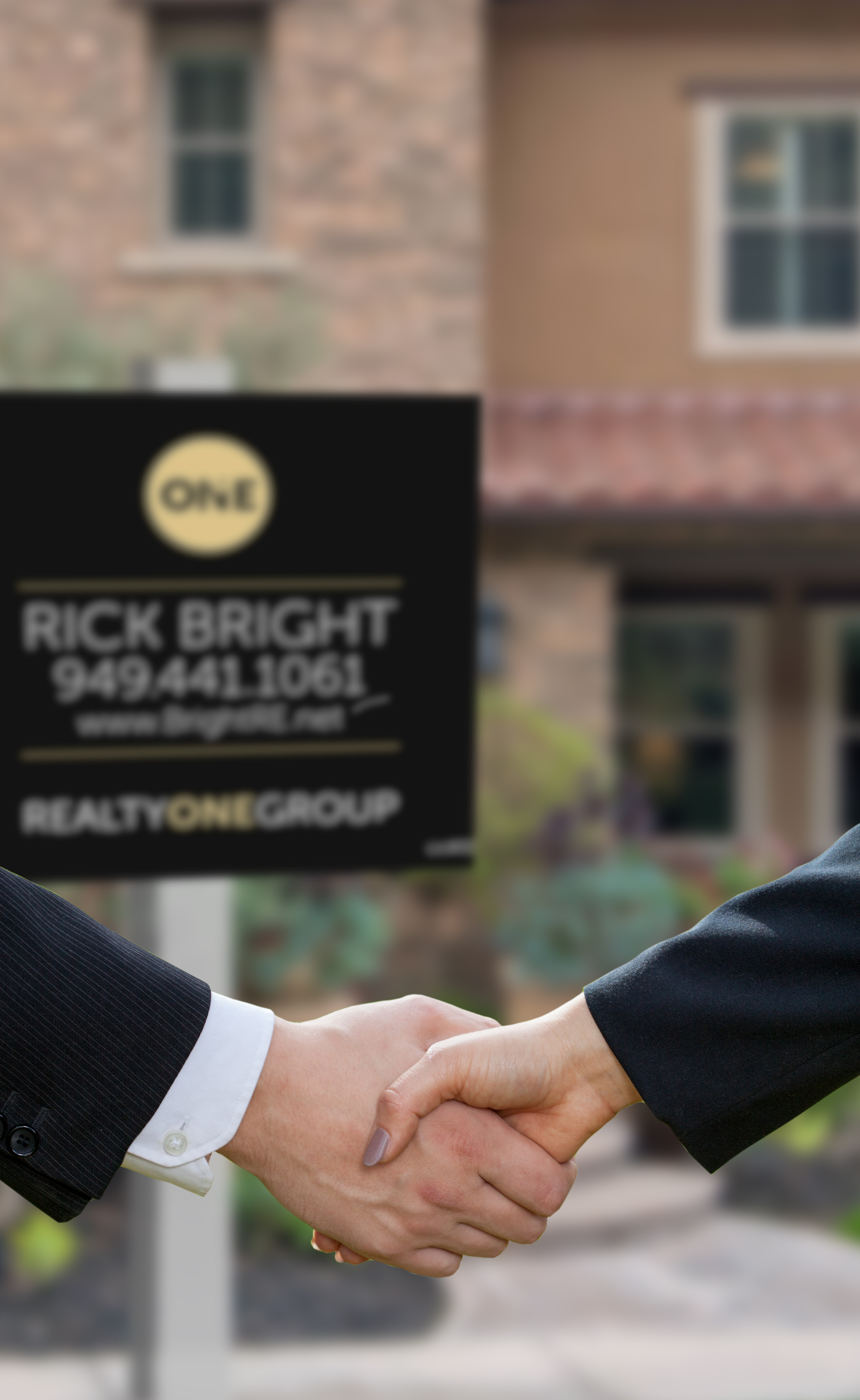people shaking hands in front of real estate sign